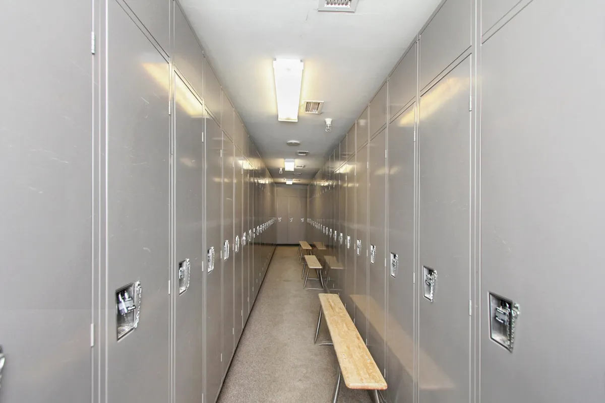 A modern locker room with sleek metal lockers and wooden benches, bathed in neutral lighting. The space feels clean, organized, and purpose-built for guests to store gear before or after their mountain adventures.