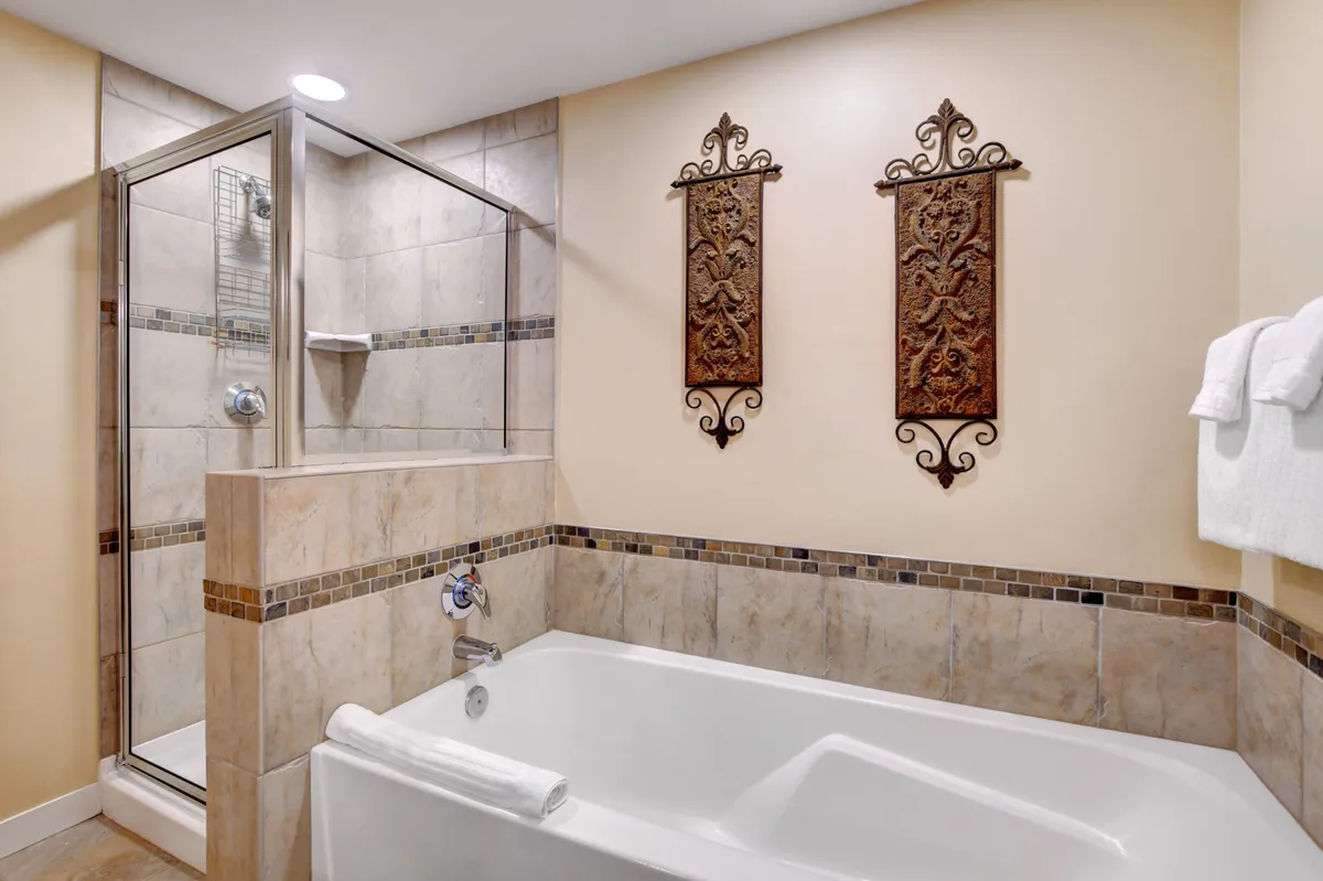 A stylish bathroom with a bathtub, shower enclosure, and decorative wall art. The space is modern and tranquil, reflecting a spa-like quality for bathing and relaxation.